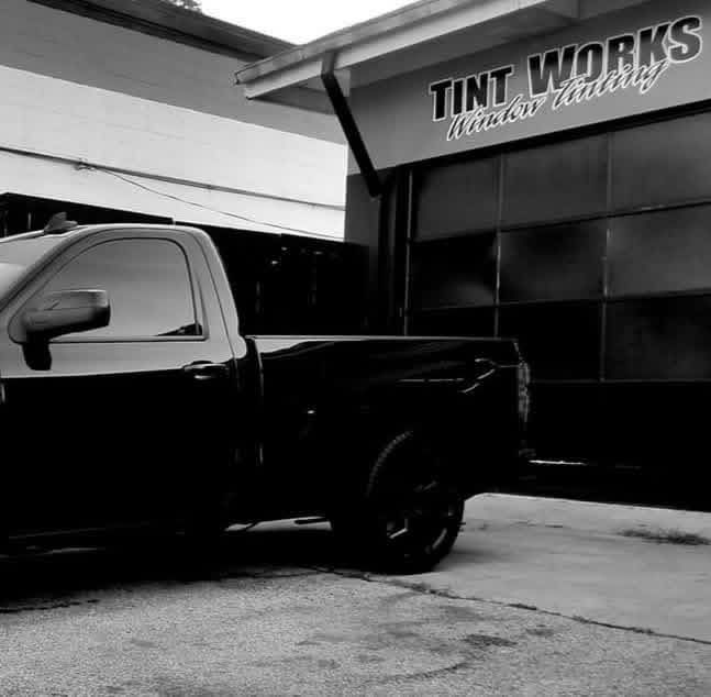 A black pickup truck parked in front of a shop named 