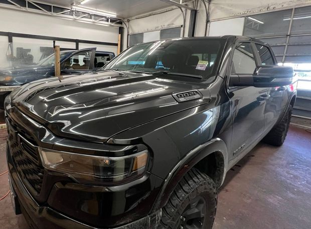 A black Ram pickup truck parked in a well-lit garage, viewed from the front-quarter angle.