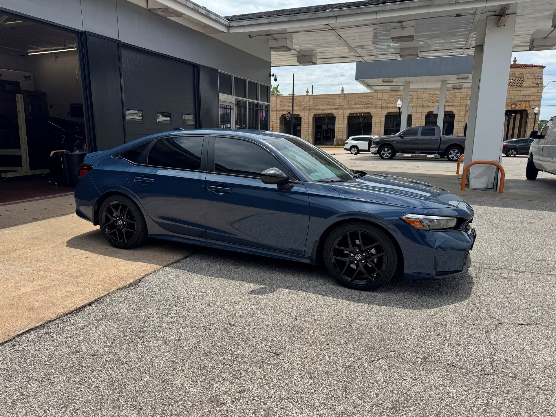 Blue sedan parked under a canopy at a service station