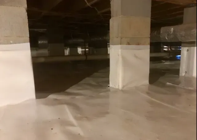 A room with a lot of pillars and a lot of white sheets on the floor.