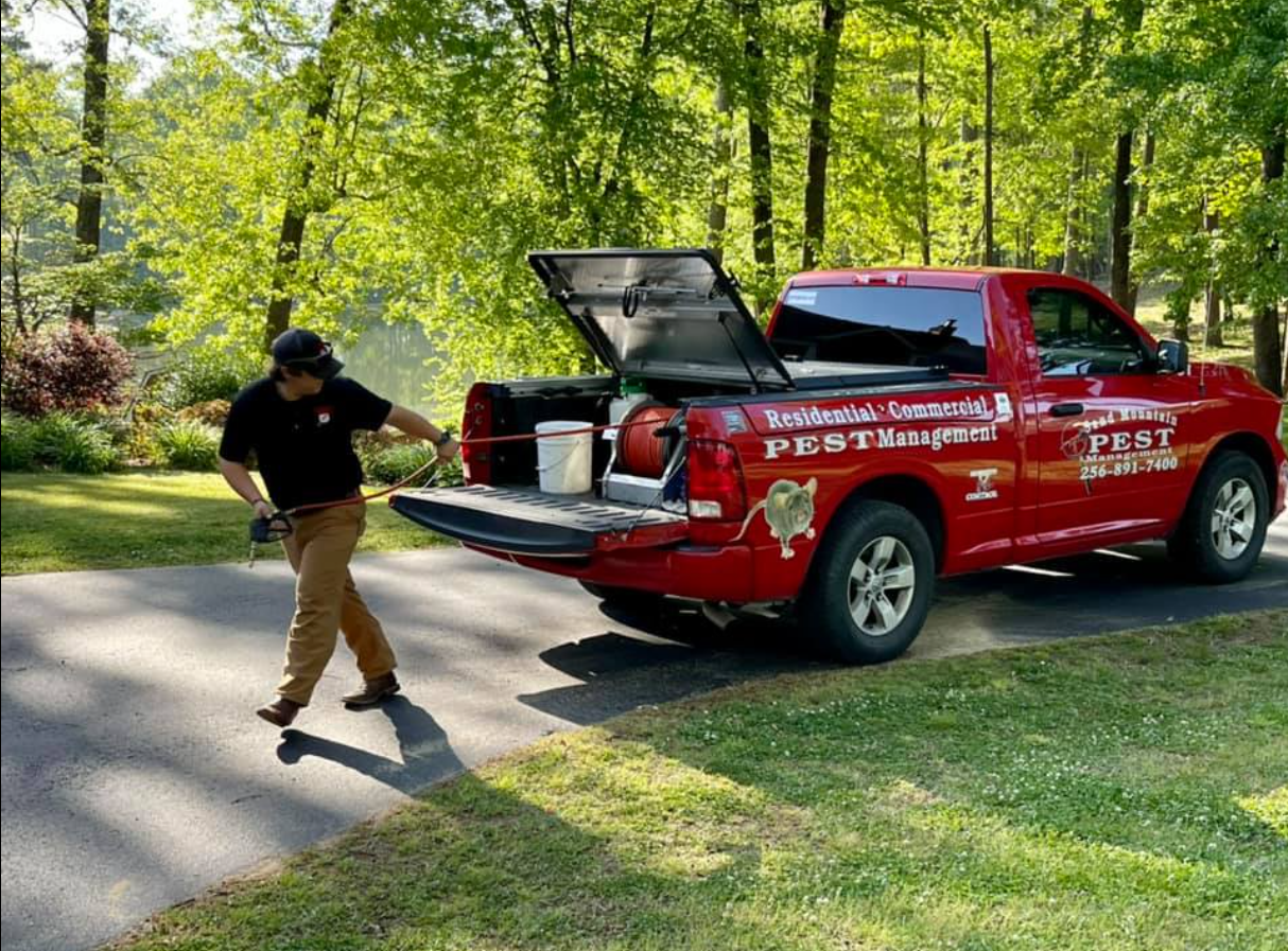 A man is walking towards a red truck with the back door open.