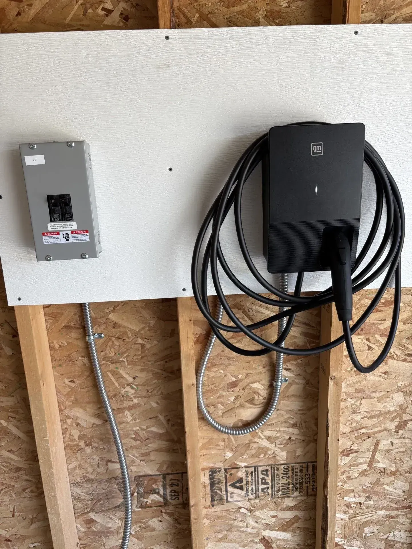An electric vehicle charger and electrical panel mounted on a wooden wall