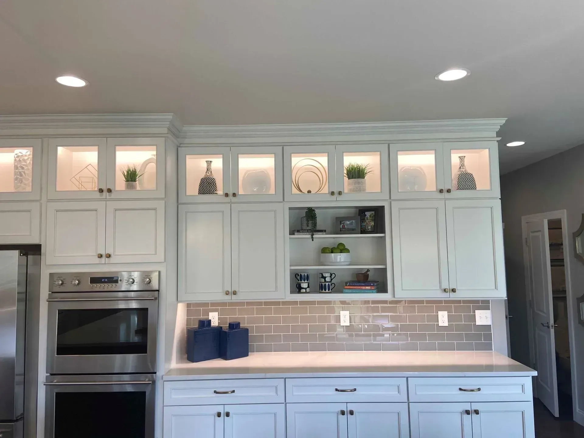 White kitchen cabinets with recessed lighting, integrated appliances, and decorative items