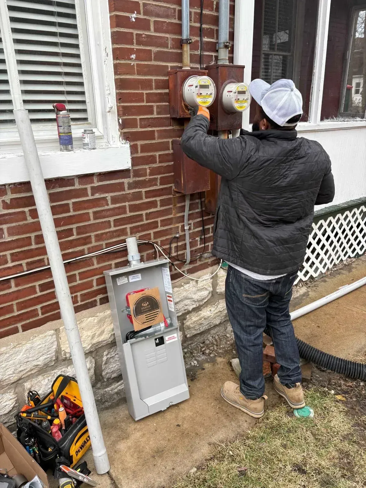 Electrician working on utility meters attached to a brick building