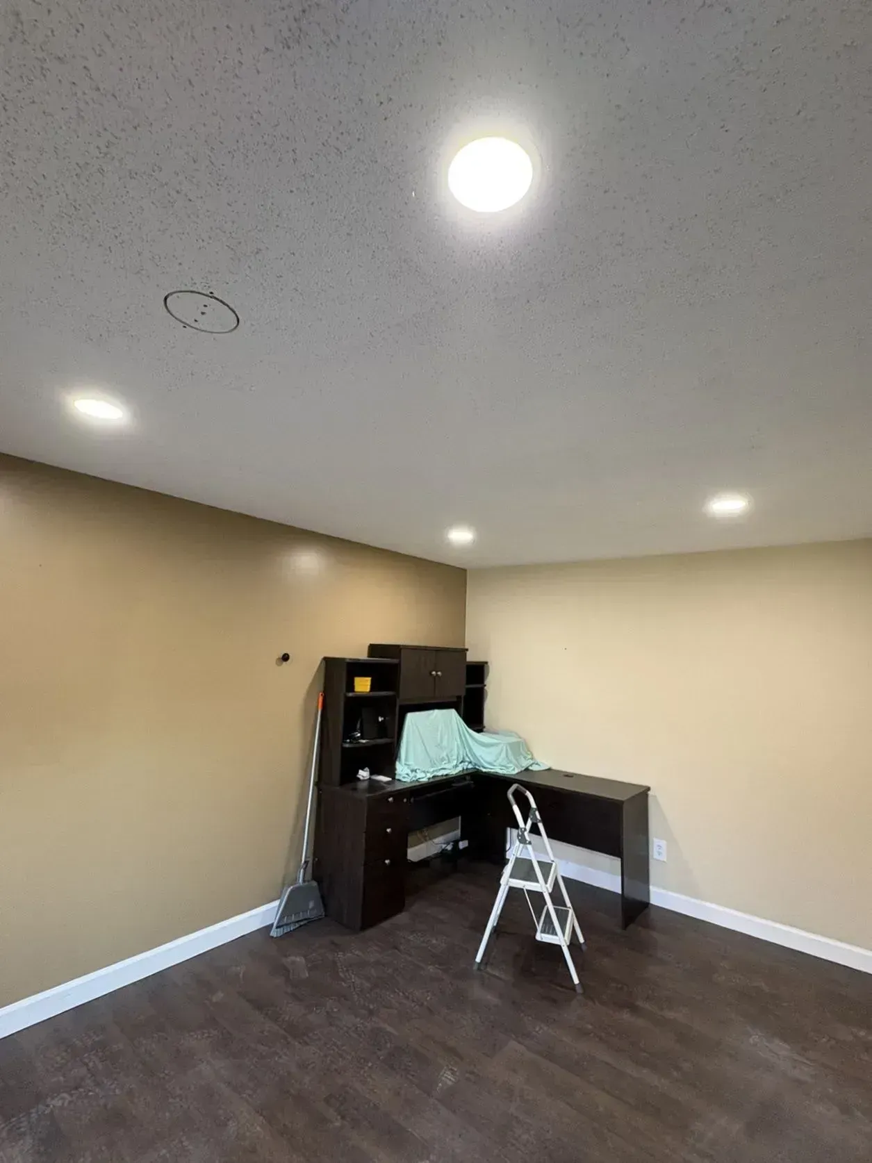 An empty room with brown walls and a dark desk, lit by ceiling lights