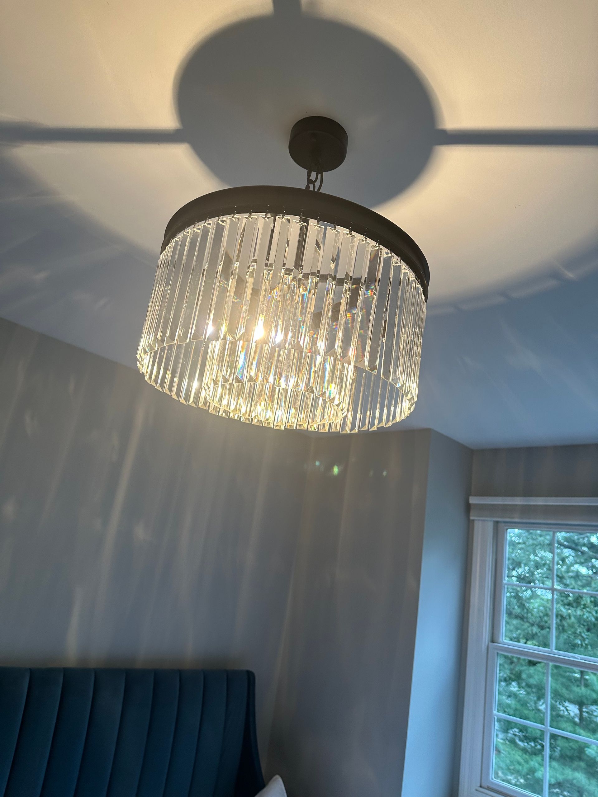 Crystal chandelier hanging from ceiling, casting a circular shadow.