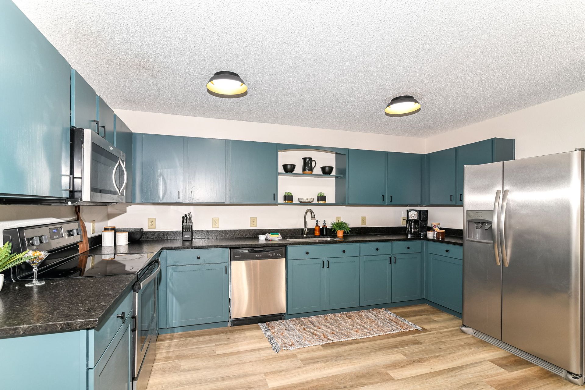 Kitchen with blue cabinets, stainless steel appliances, and dark countertops.