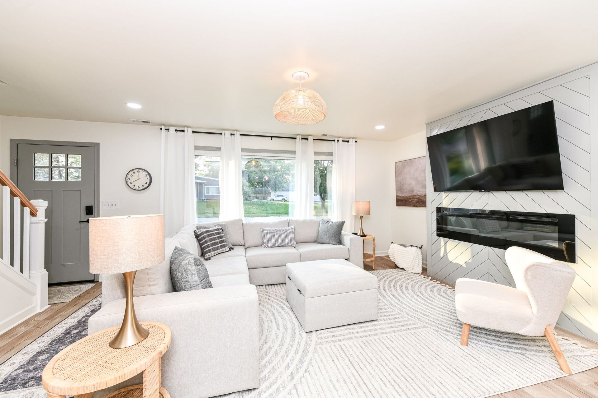 Cozy white living room with sectional sofa, fireplace, rug, and large windows.