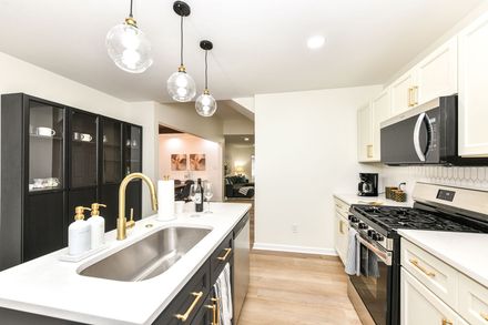 Modern kitchen with black and white cabinets, gold hardware, and pendant lights.