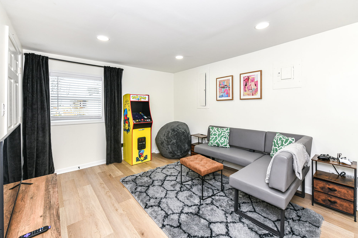 Living room with a gray sectional sofa, arcade game, and wooden floor.