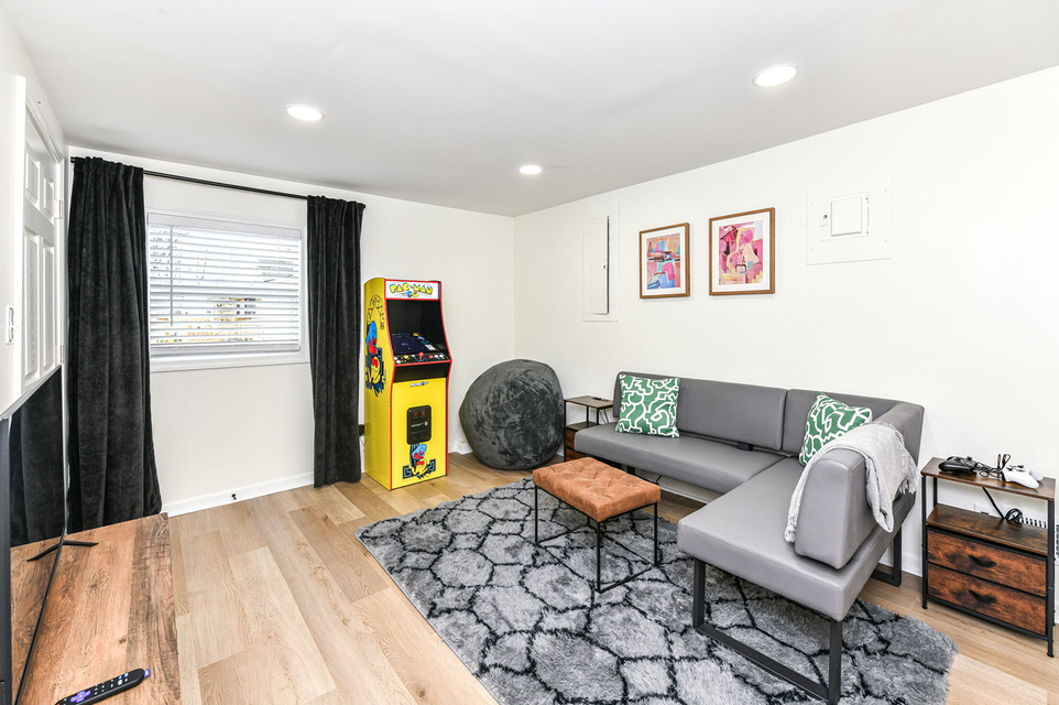 Living room with a gray sectional sofa, arcade game, and wooden floor.