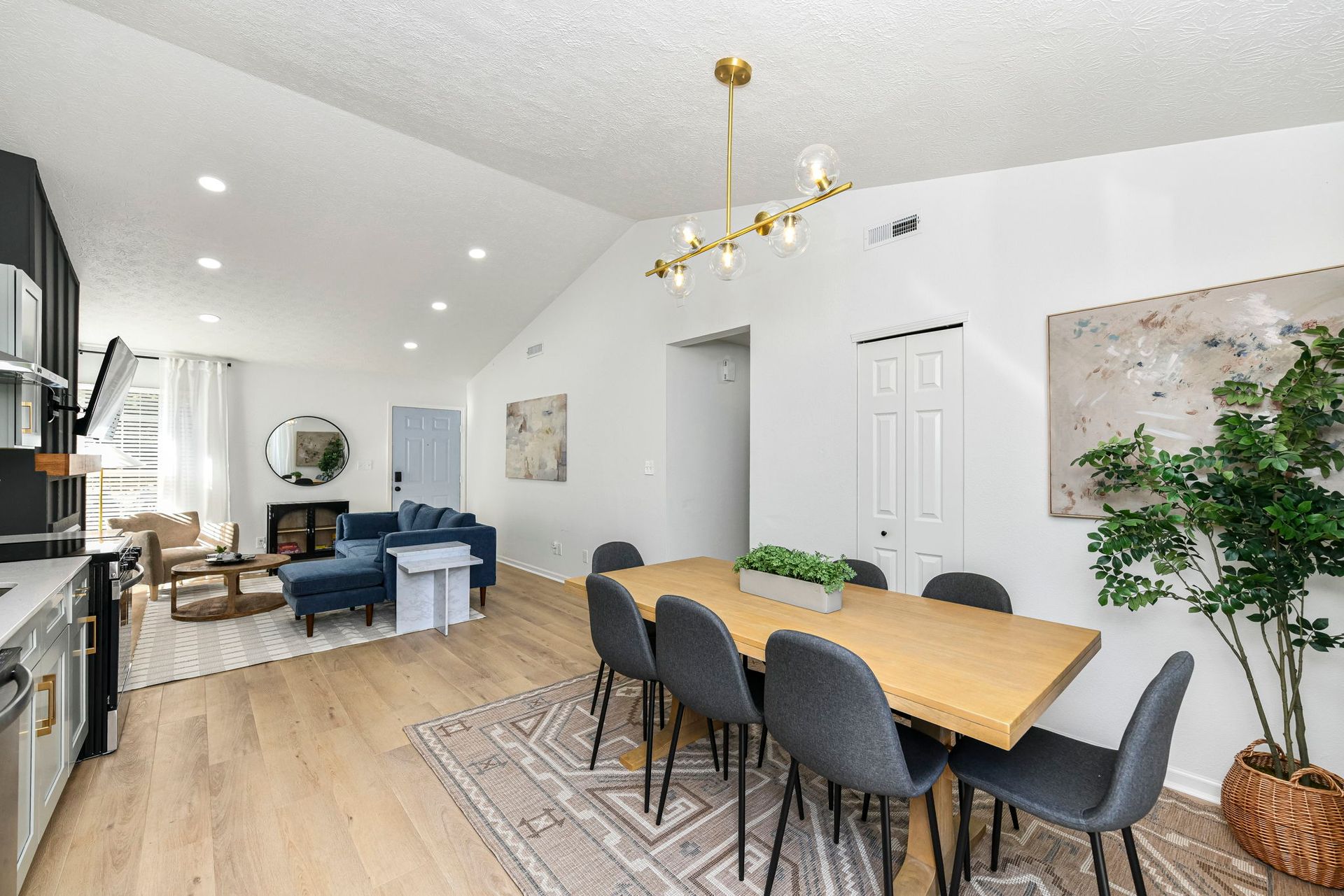 Open-concept living space with dining table, chairs, and living area with blue sofa and fireplace.