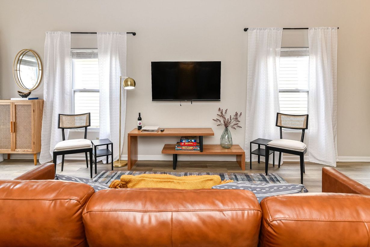 Two men shaking hands across a table, woman smiles. Office setting, window in background.