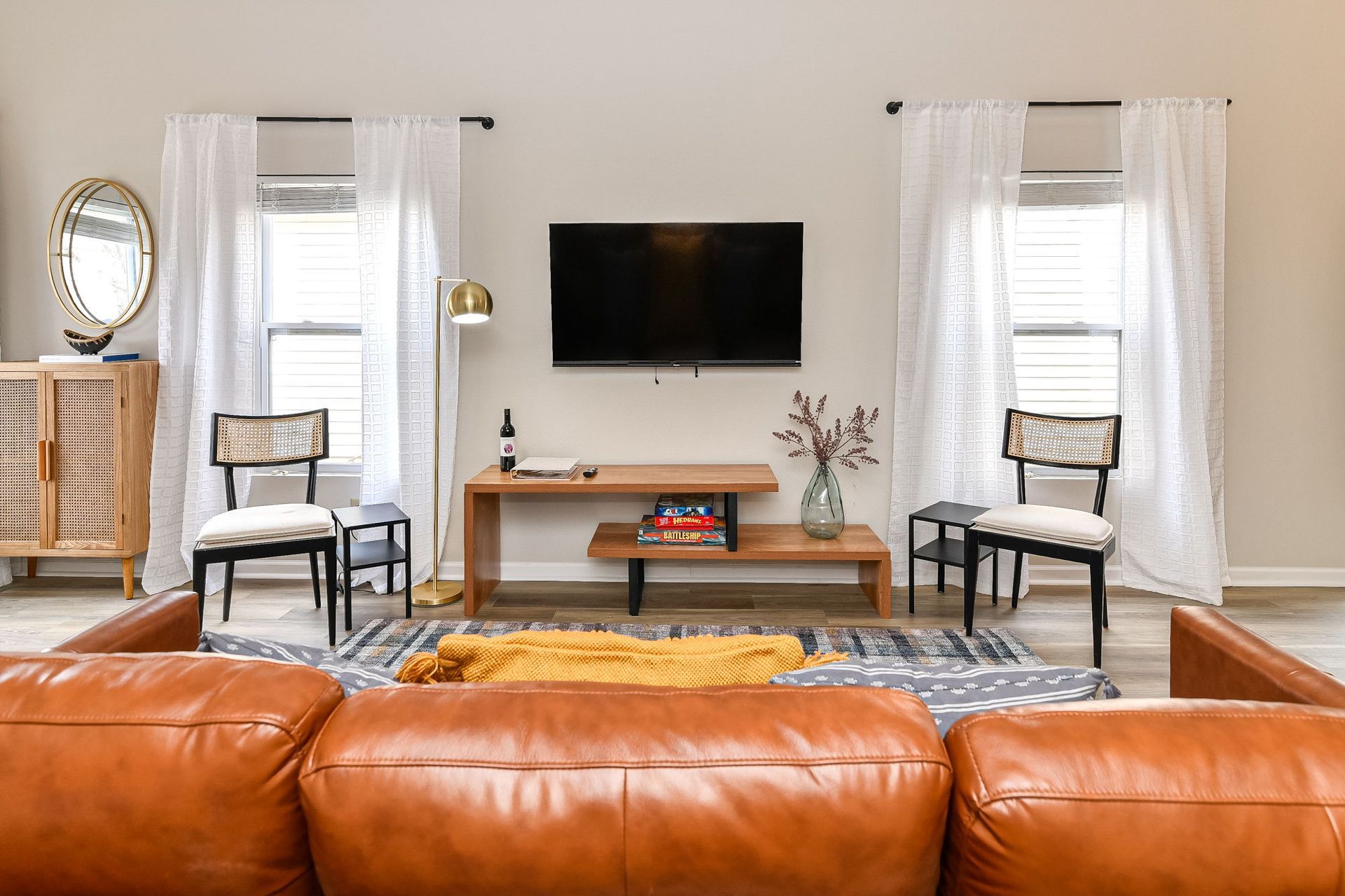 Two men shaking hands across a table, woman smiles. Office setting, window in background.