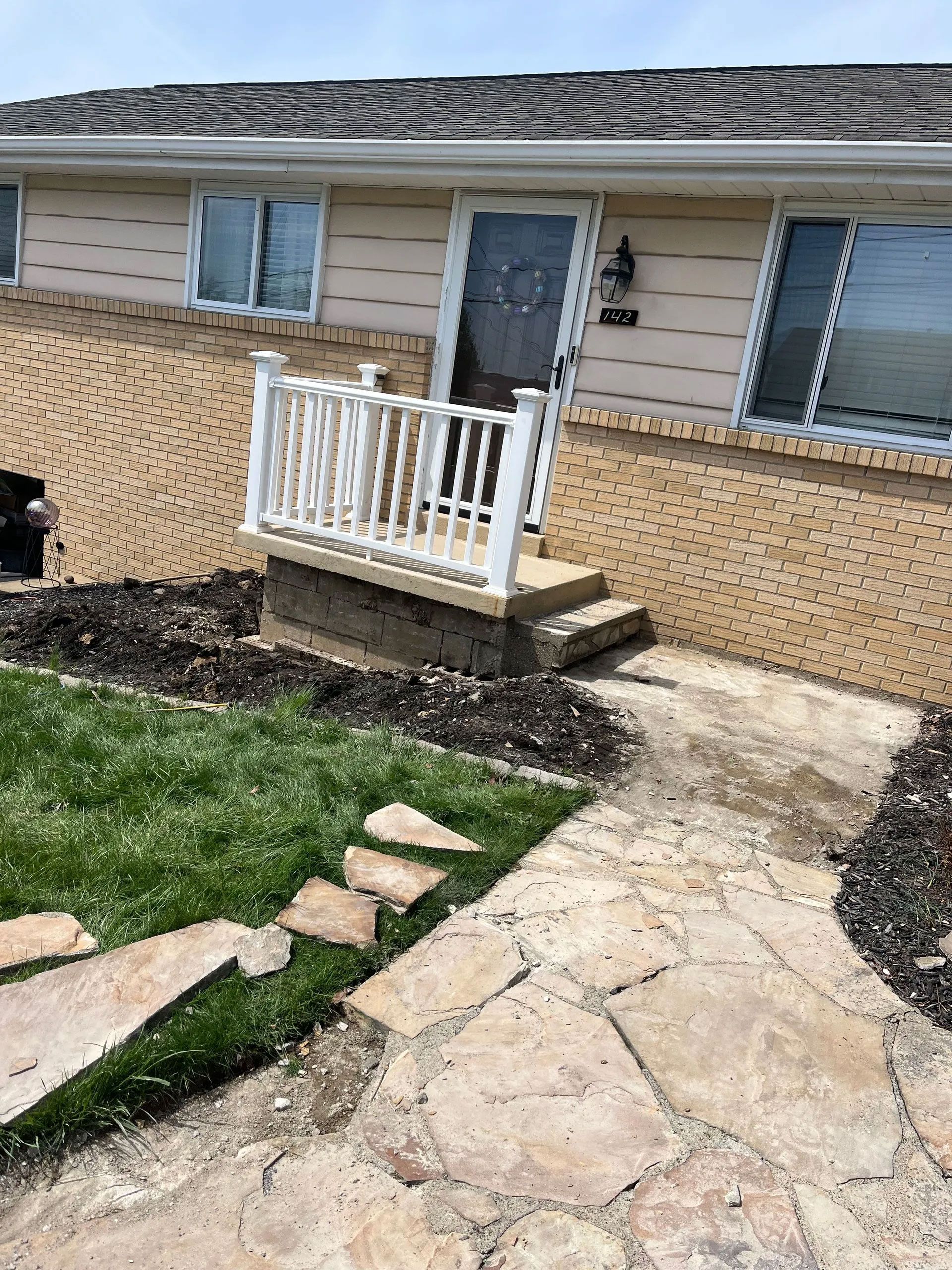 House exterior with flagstone path, steps, and white railing leading to the front door.