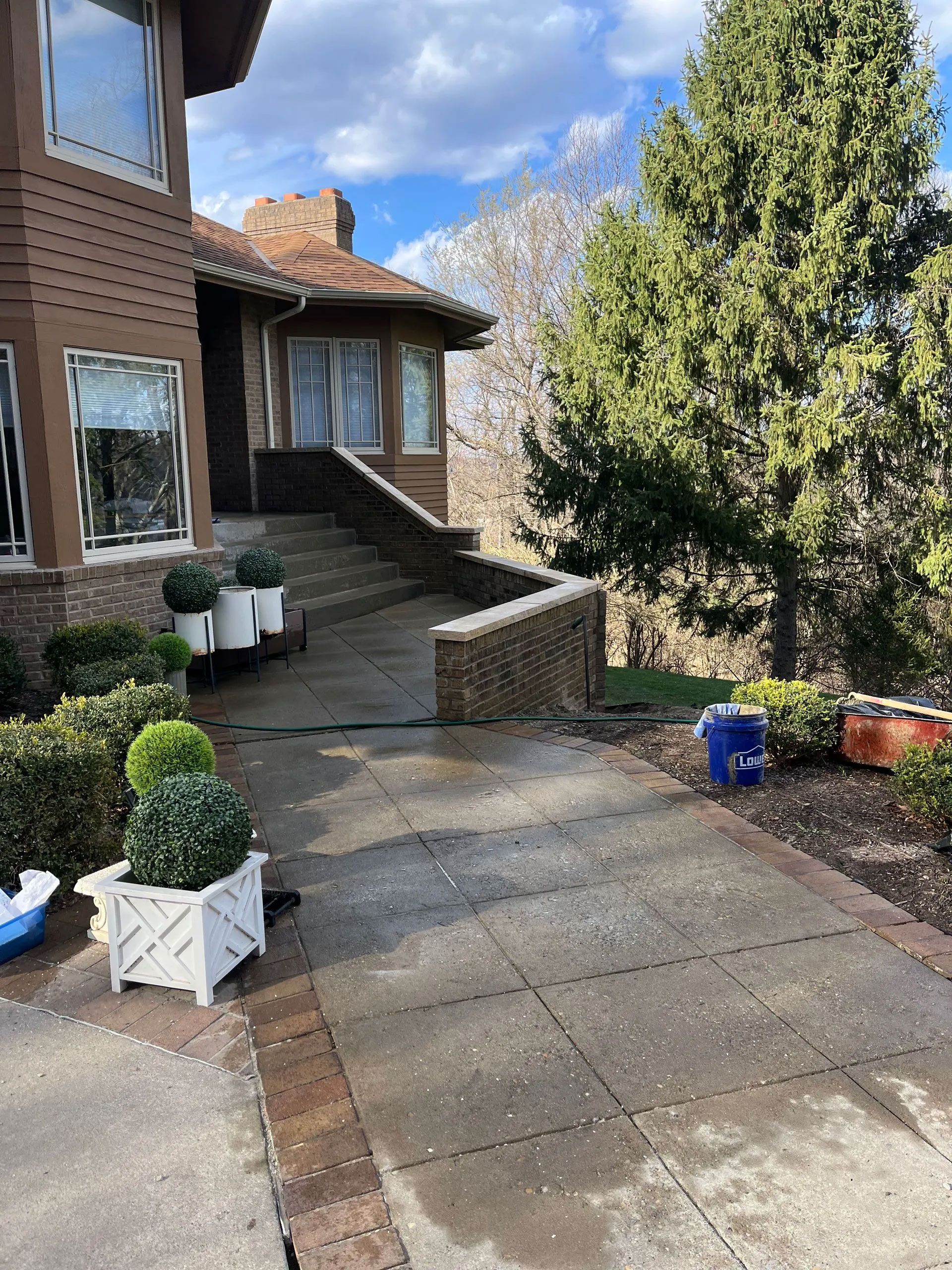 A house with brown siding and a concrete walkway leading up to the front door.
