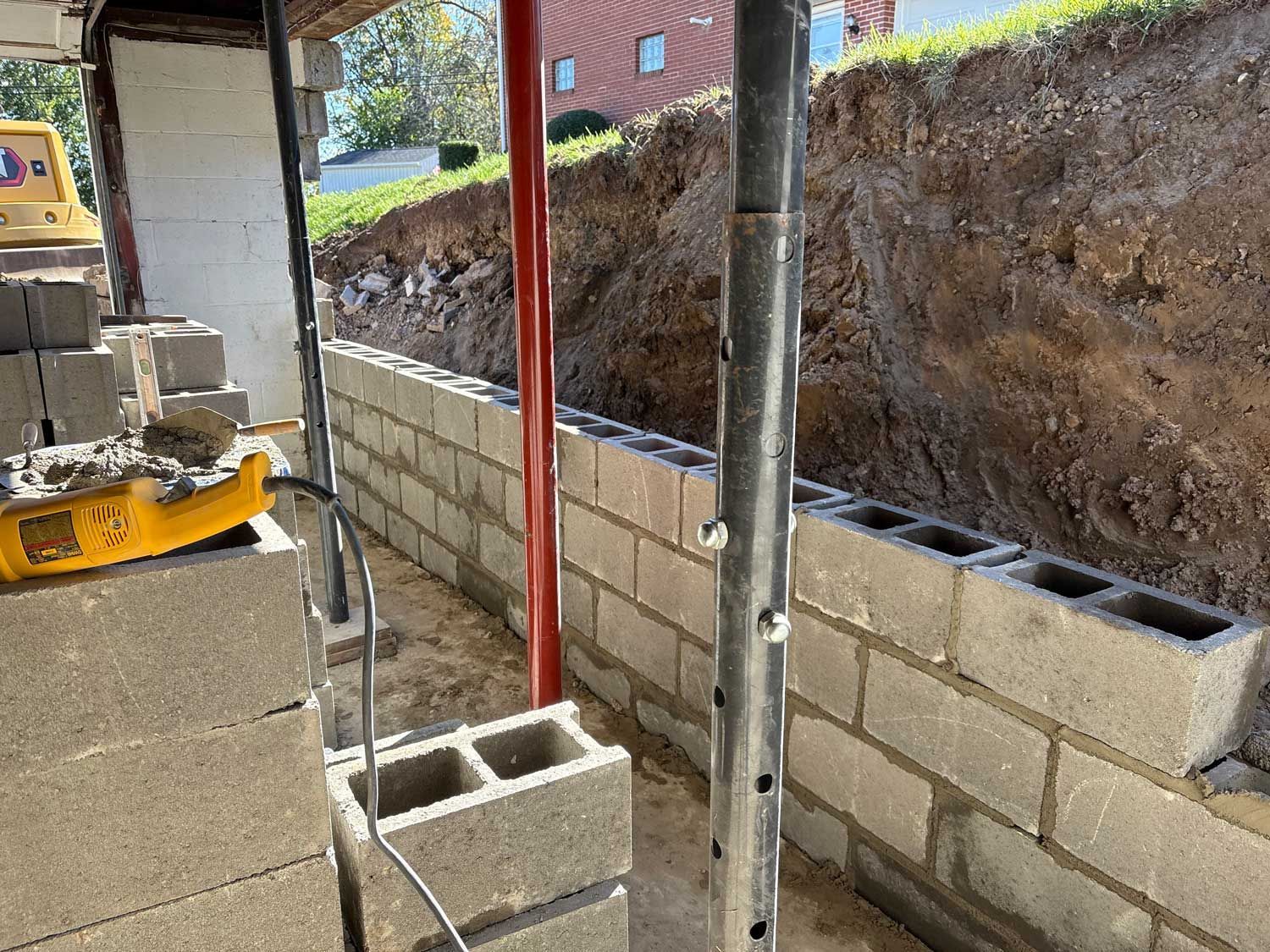 Construction site with cinder block walls, red support beams, and exposed earth.