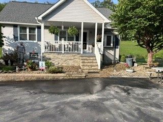 Single-story house with a covered front porch, stone steps, and a driveway in front.