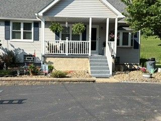 Suburban house with small front porch, steps, and landscaped front yard beside a driveway