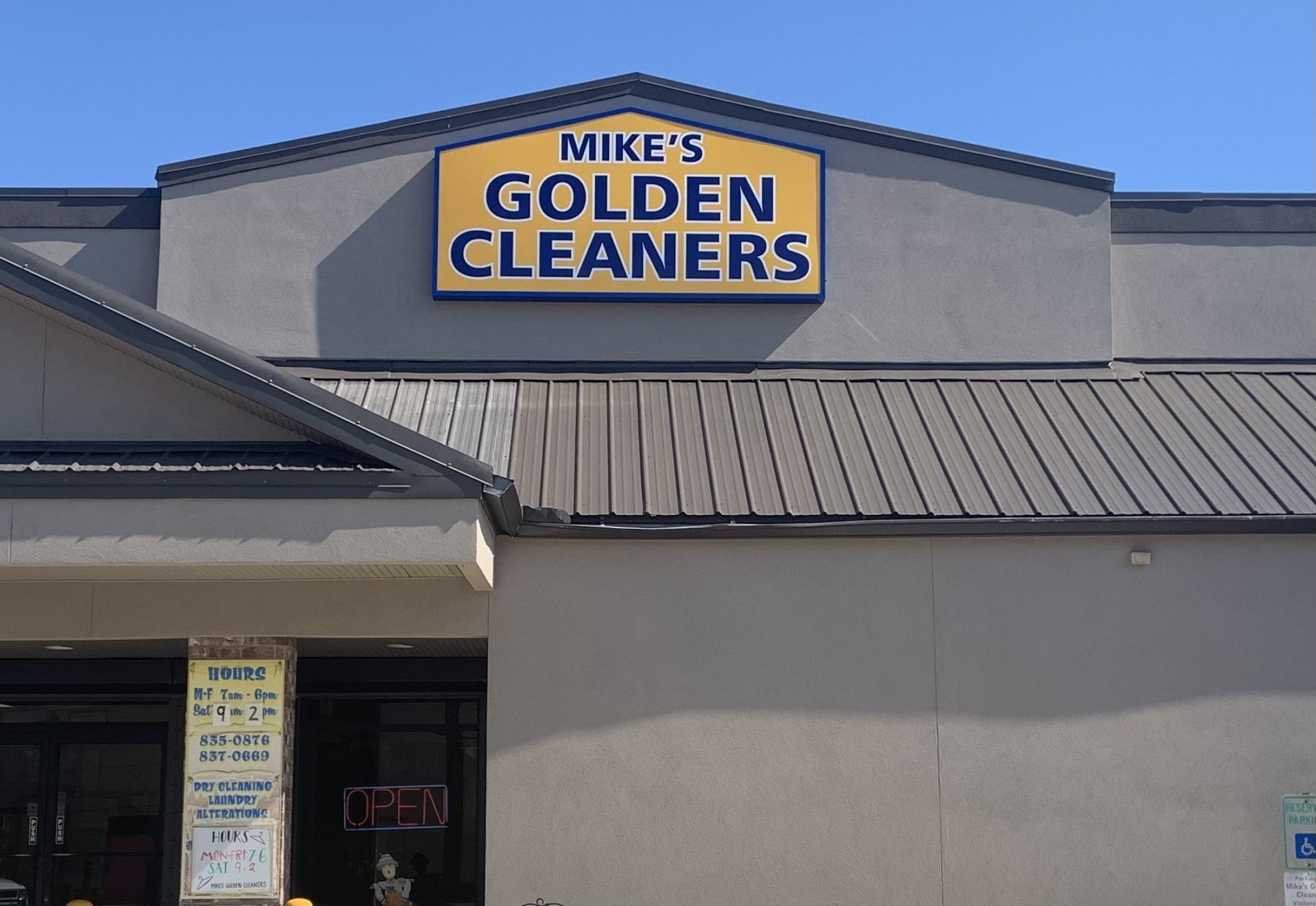 Storefront sign reading “Mike’s Golden Cleaners” on a beige building with a metal roof.