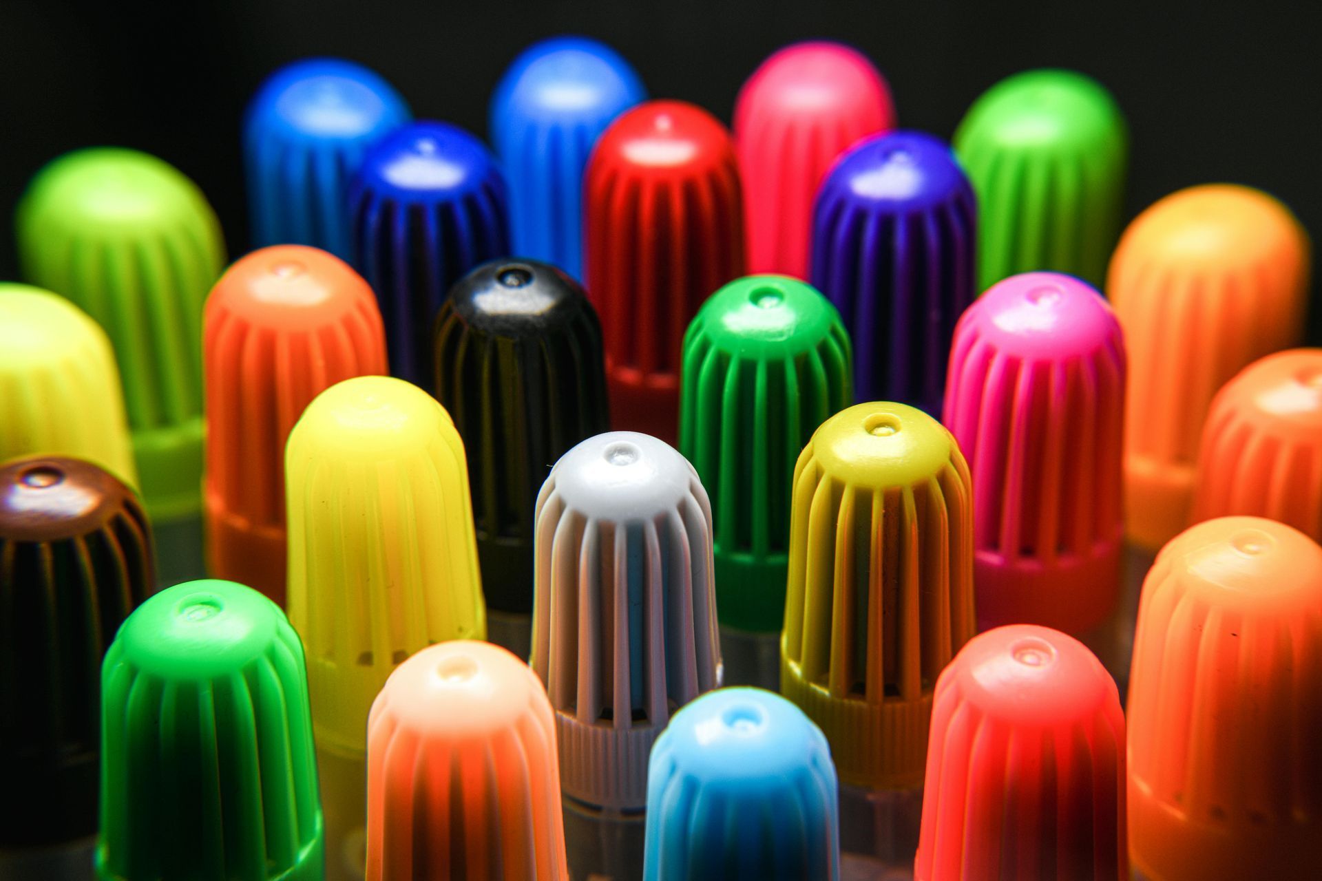 Rows of colorful ribbed domes or caps in red, blue, green, yellow, orange, pink, and black, close-up view