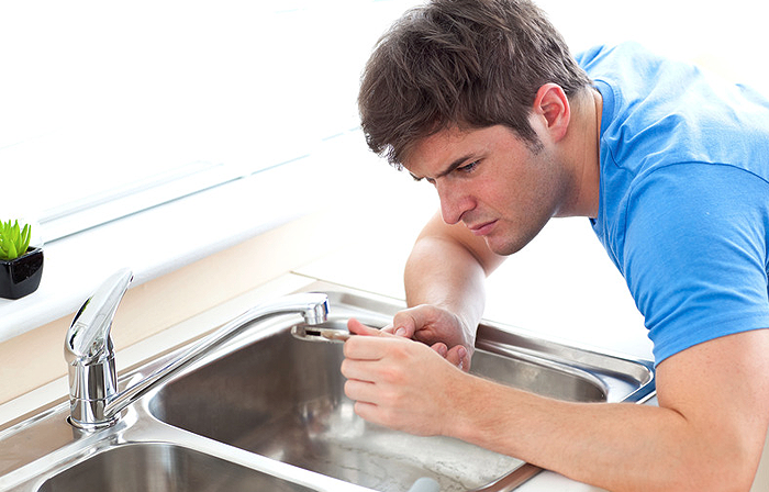 Man looking at a leaky faucet