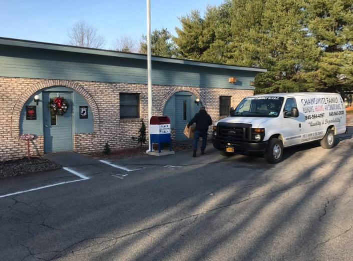 Two people by a brick storefront and white van in a parking lot at dusk