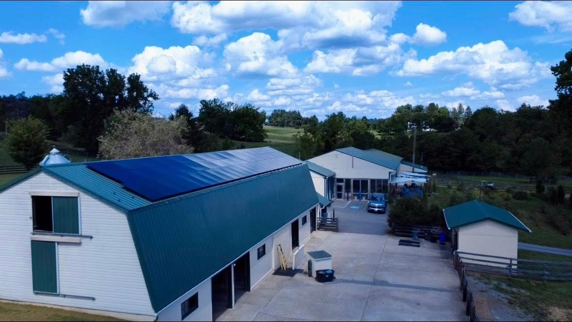 Rural farm buildings with blue roofs under a bright, cloudy sky