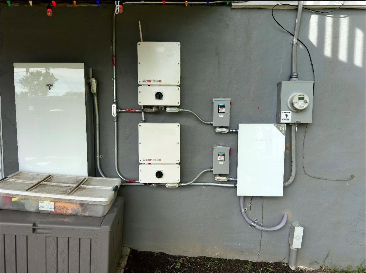 Outdoor wall with electrical meters, utility boxes, and conduits beside a metal bin