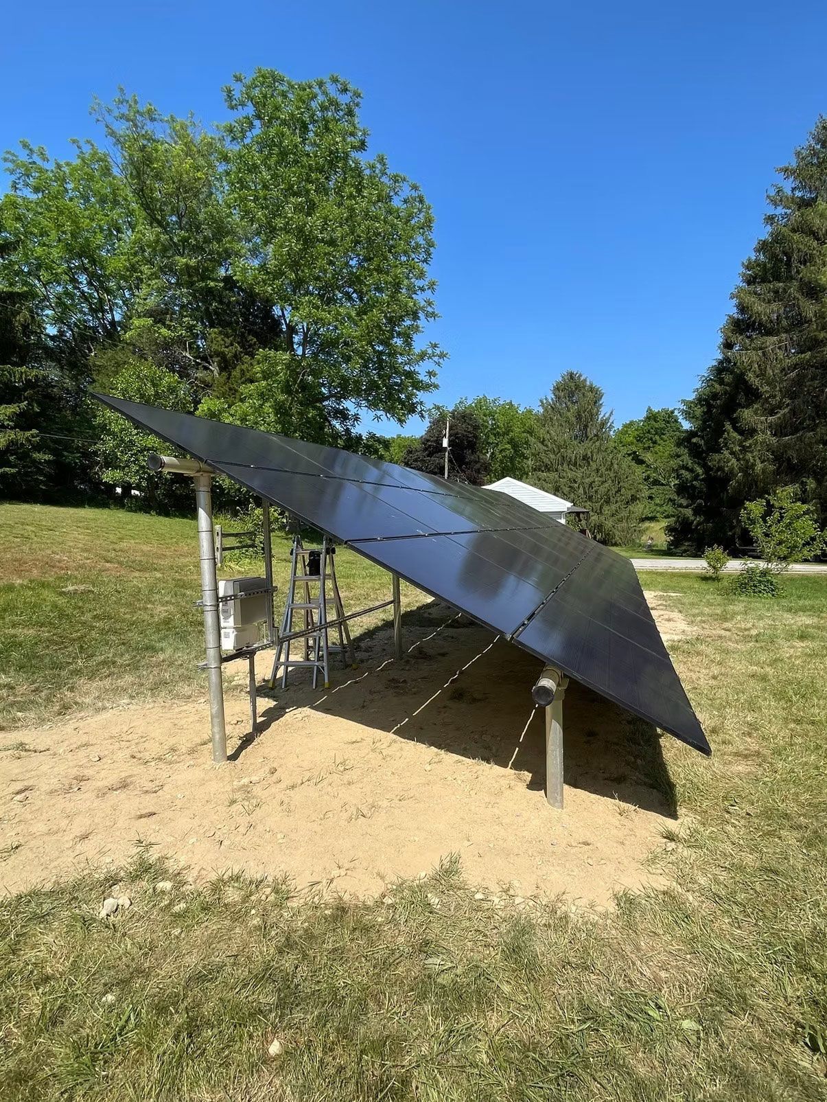 Metal solar panel mounted on a frame in a grassy field under a bright blue sky