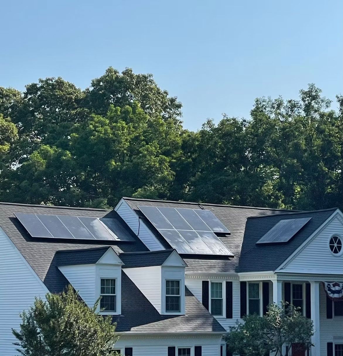 Suburban house with rooftop solar panels under a clear blue sky