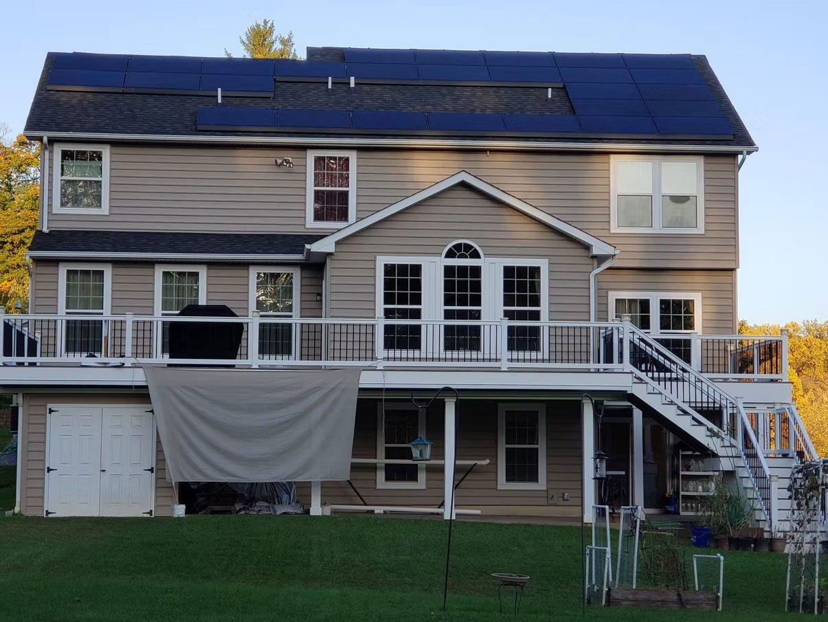 Two-story house with solar panels on the roof, front porch, and exterior staircase at dusk