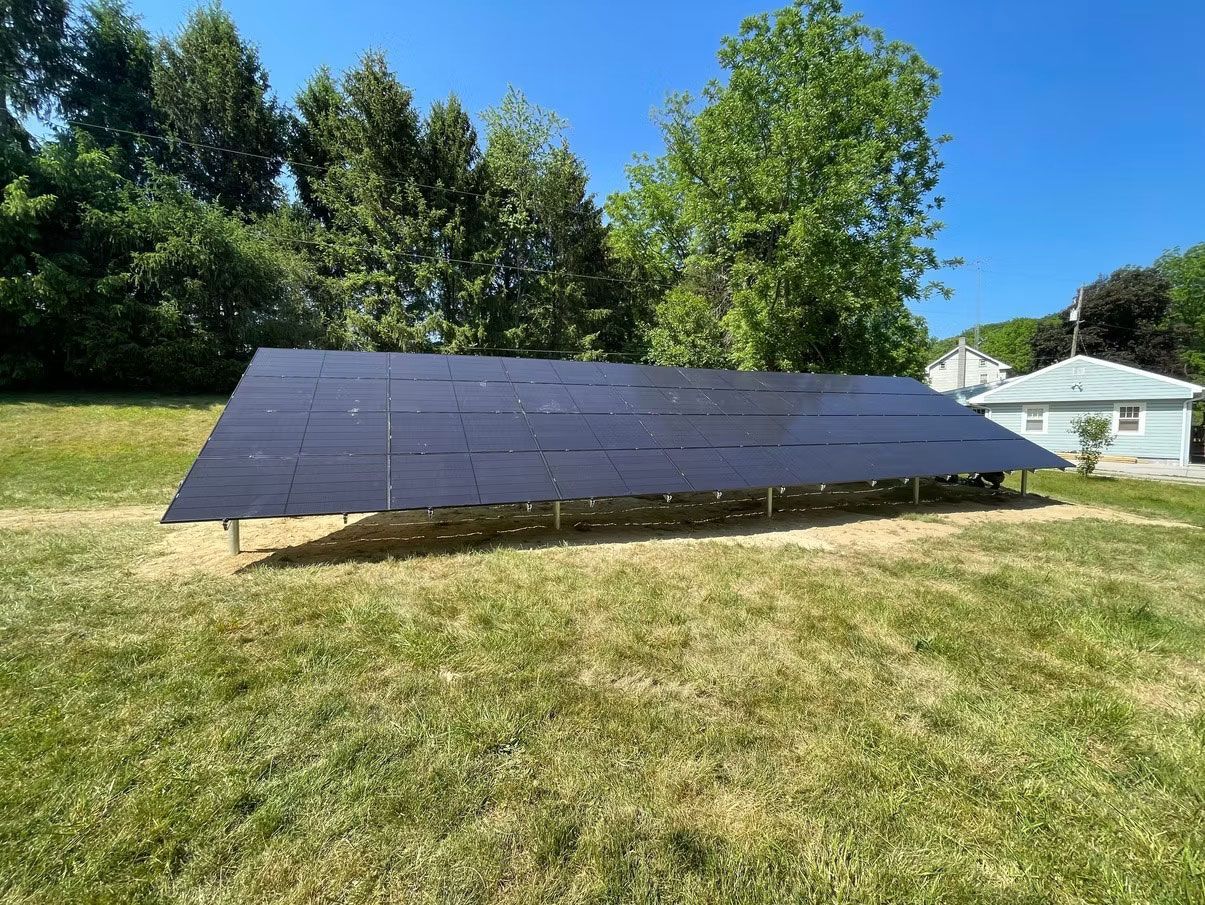 Large ground-mounted solar panel array in a grassy yard under a blue sky