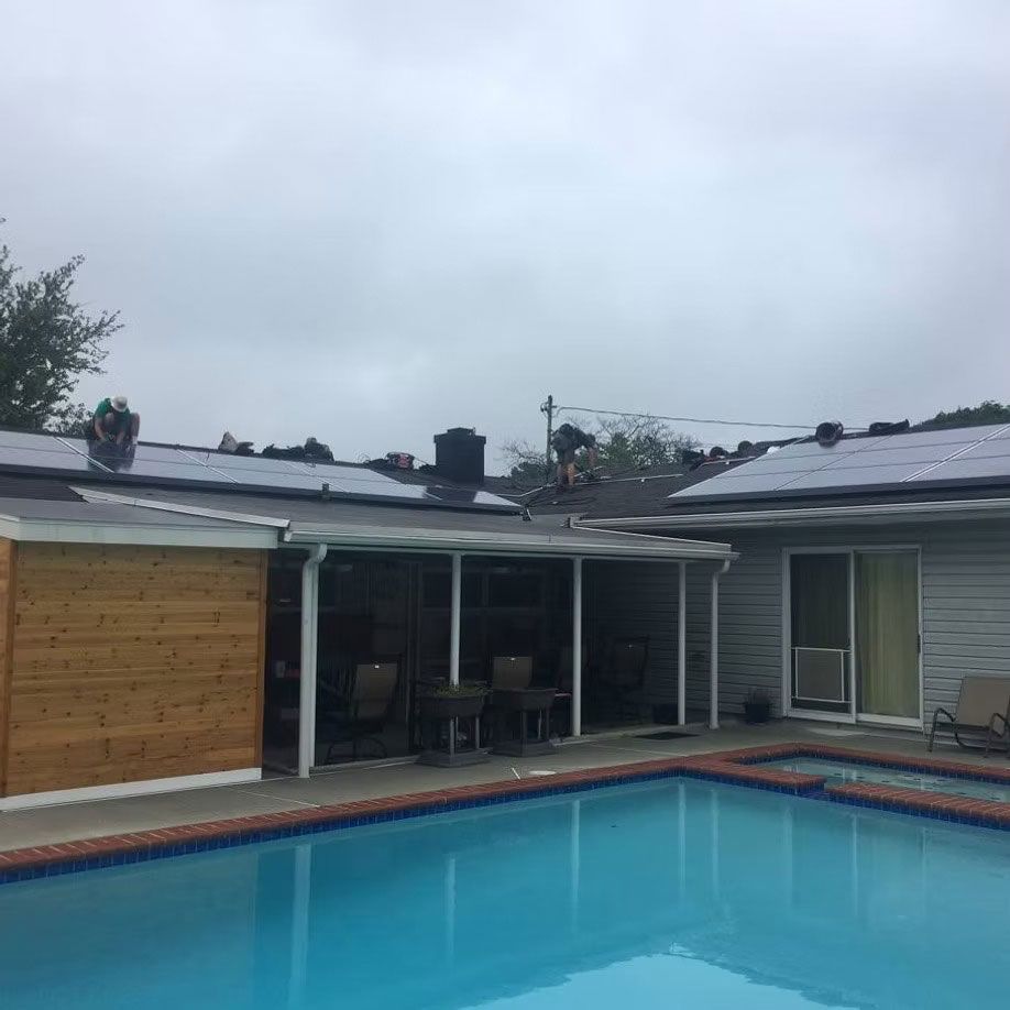 Backyard pool with a covered patio and single-story house under a cloudy sky