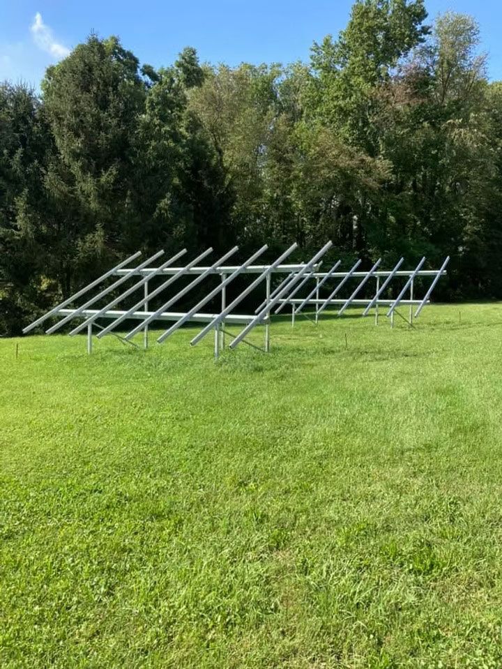 Metal frame structure on a green lawn with trees in the background