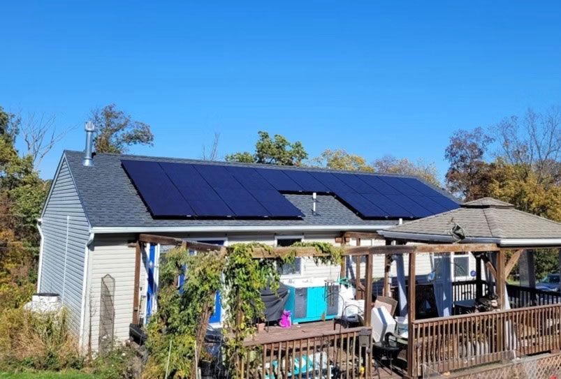 House with solar panels and a porch under a clear blue sky
