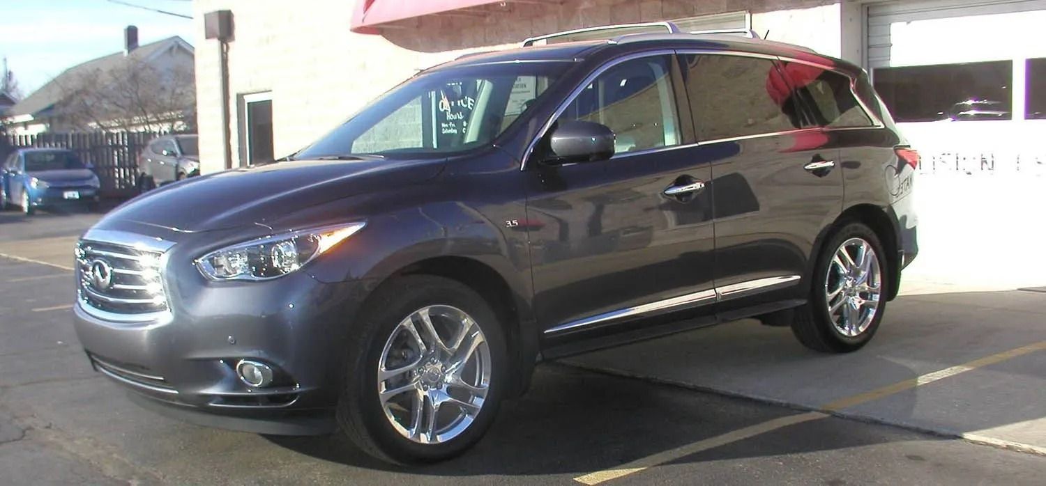 Dark gray Infiniti SUV parked in front of a building with a pink awning.
