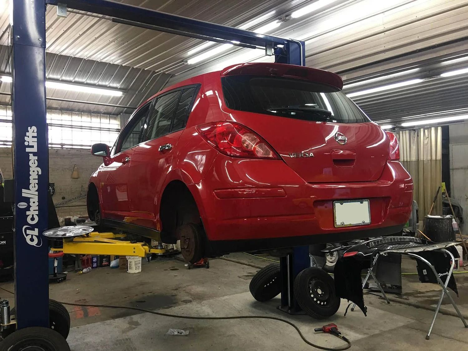 Red car raised on a lift in a repair shop.