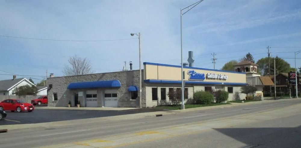 Building with blue awning, sign, and cars parked in front.