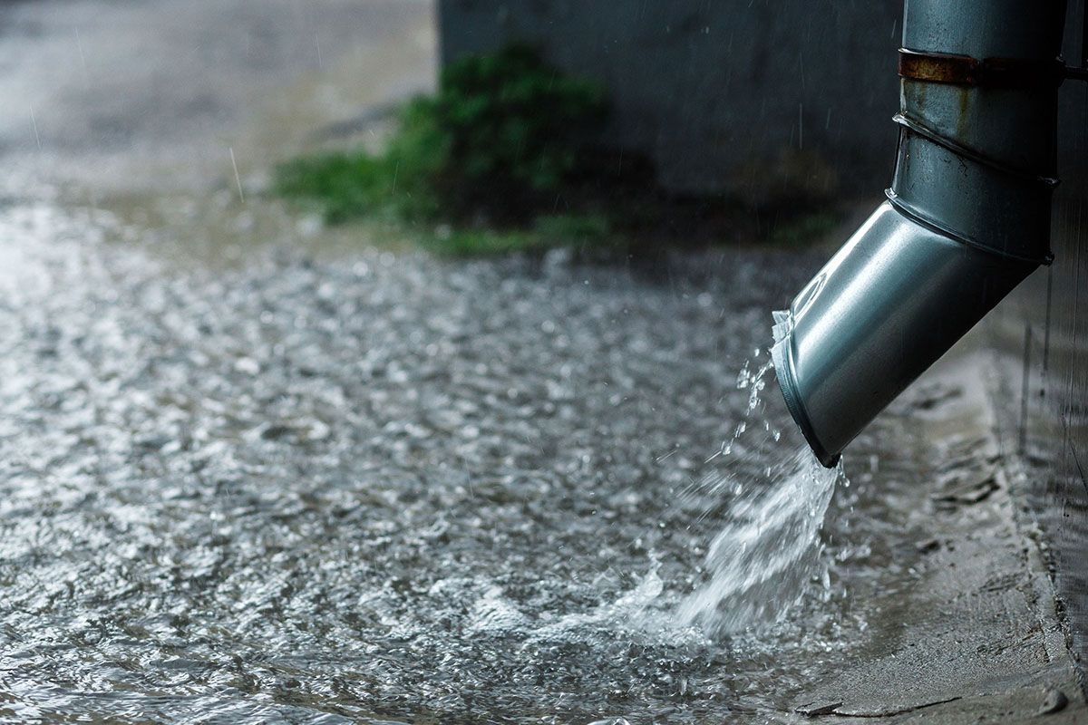 Water is coming out of a drain pipe on a rainy day.