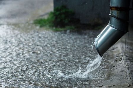 Water is coming out of a drain pipe on a rainy day.