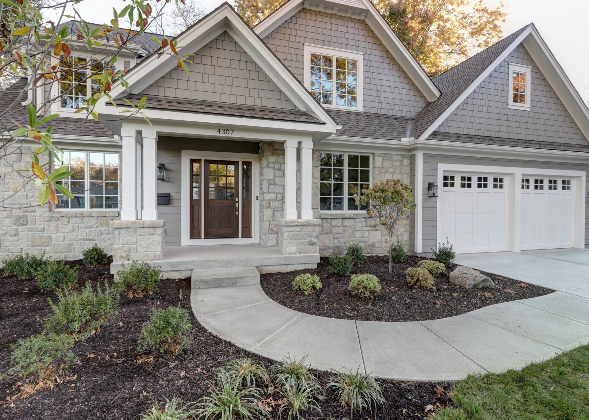A large house with a gray roof is sitting on top of a lush green lawn.