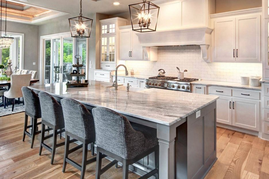 A kitchen with white cabinets, granite counter tops, and a large island