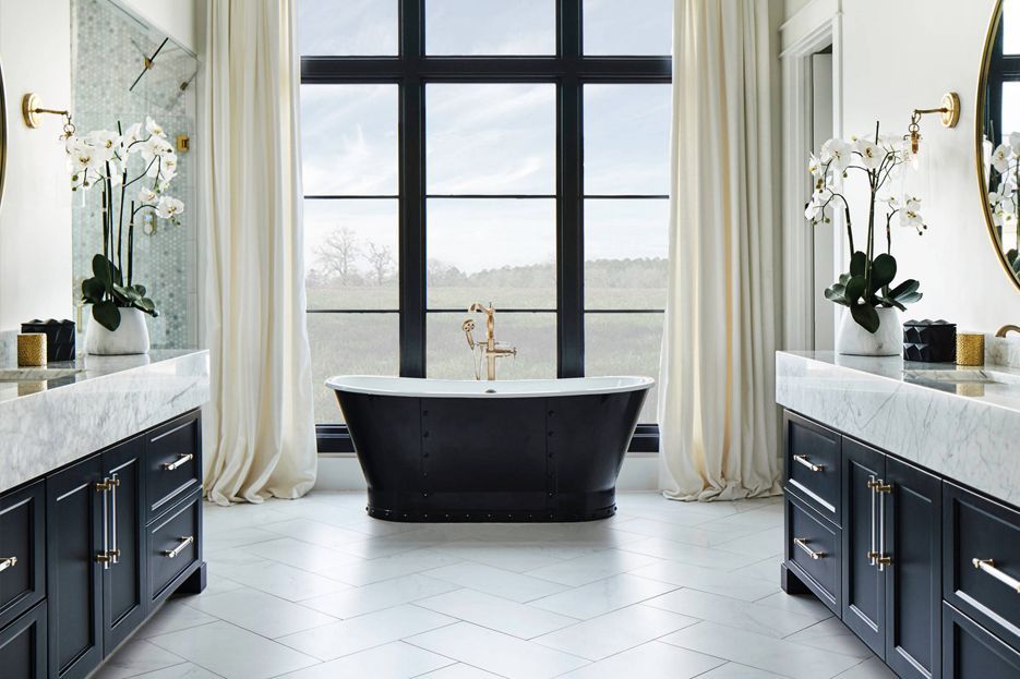 A bathroom with two sinks, a tub, and a large window