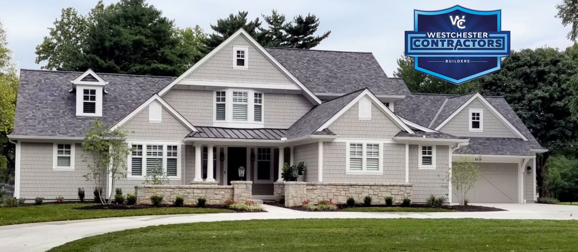 A large house with a gray roof is sitting on top of a lush green lawn.