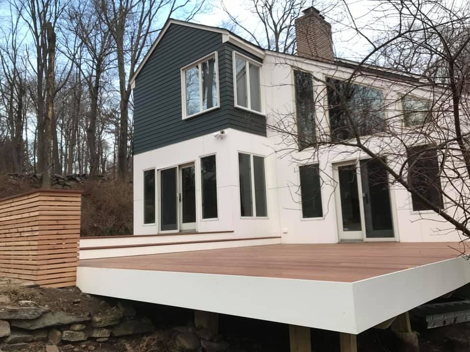 A white house with a wooden deck in front of it.
