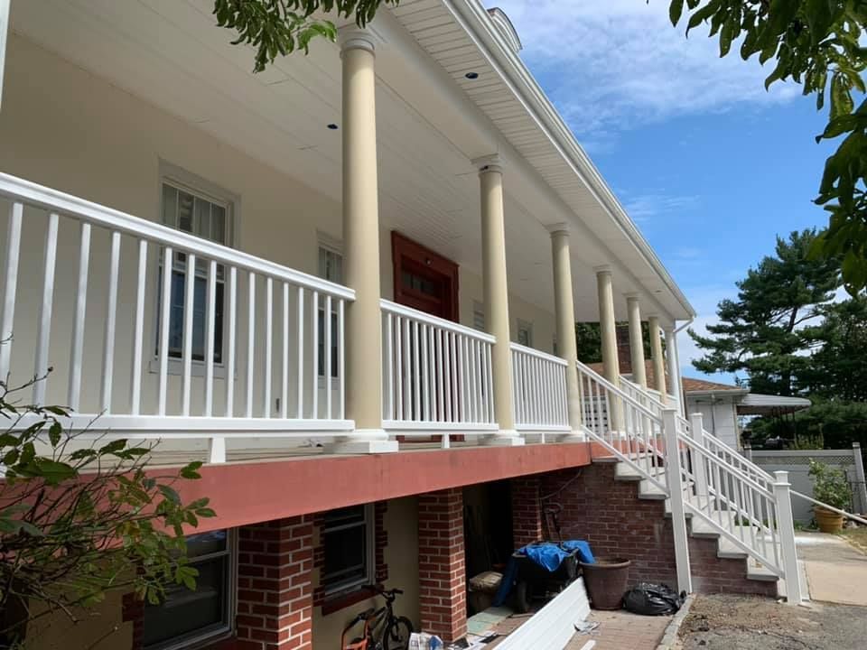 A large house with a white railing and stairs.