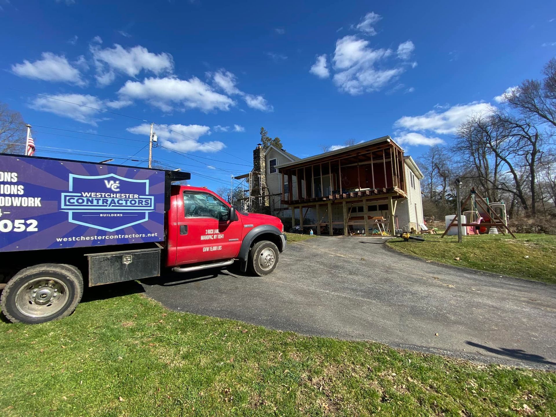 A red truck is parked in front of a house under construction.