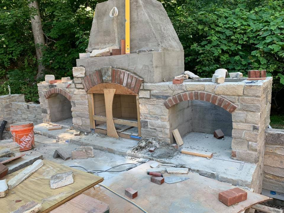 A brick fireplace is being built in a backyard.