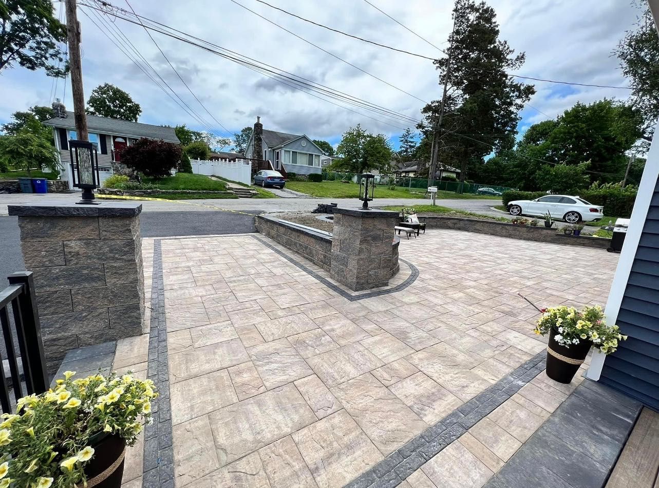 A brick patio with potted plants in front of a house.